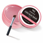 Open and closed pink PERMANIA lash glue balm jars with a flat applicator brush on a white background.